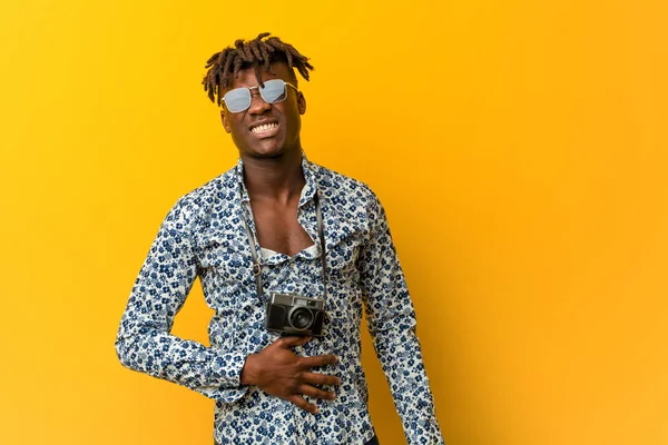 Young black rasta man wearing a vacation look touches tummy, smiles gently, eating and satisfaction concept.