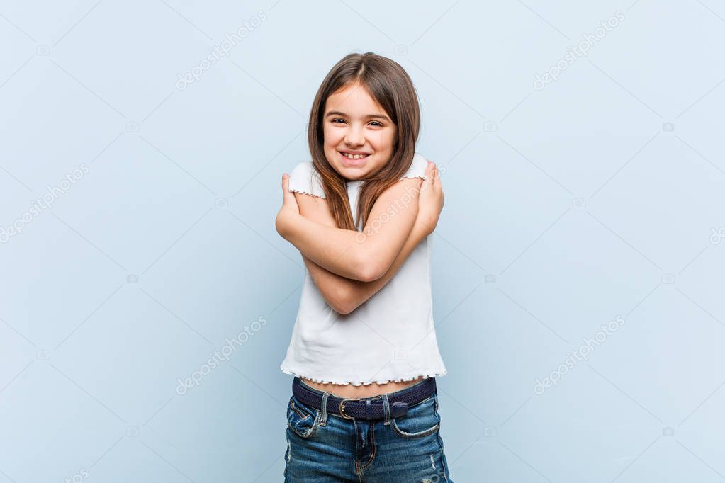 Cute girl hugs himself, smiling carefree and happy.