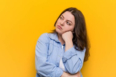 Genç kıvrımlı artı üzgün ve dalgın hissediyor boyutu kadın, kopya alanı bakarak.