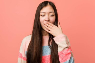 Genç, havalı Çinli kadın esniyor. Yorgun bir jest yapıyor. Ağzını onunla kapatıyor..