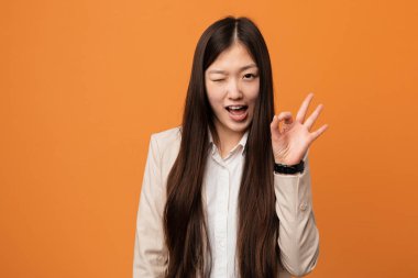 Genç iş kadını göz kırpıyor ve elleriyle iyi bir jest yapıyor..