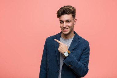 Genç iş adamı gülümseyen ve işaret eden, boş alanda bir şey gösteren doğal bir adam..