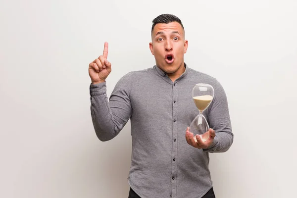 Young Latin Man Holding Sand Timer Having Great Idea Concept — Stock Photo, Image