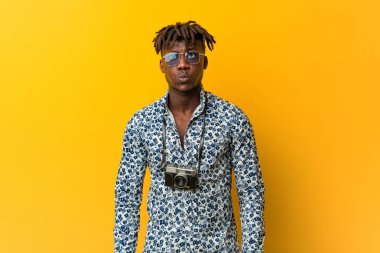 Tatil kıyafeti giyen siyah Rasta 'lı genç adam yanakları patlatıyor, yorgun bir ifadesi var. Yüz ifadesi kavramı.