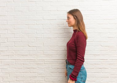 Duvarın arkasında önüne bakan havalı genç bir kadın.