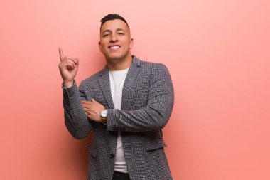 Young elegant latin man pointing to the side with finger