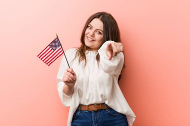 Genç, kıvrımlı, iri bir kadın, elinde Amerika Birleşik Devletleri bayrağını tutuyor..