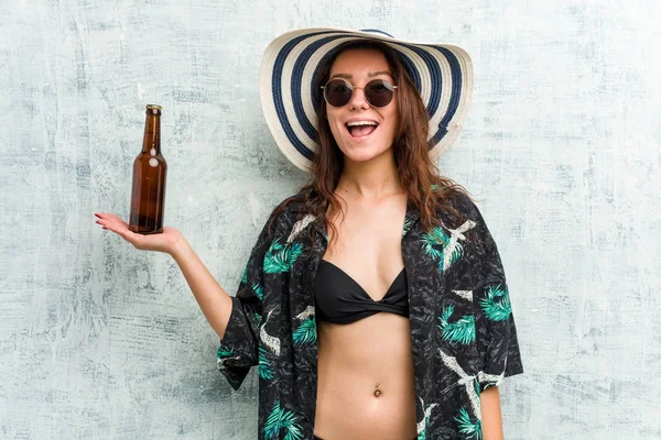 Young european woman wearing bikini and drinking a beer