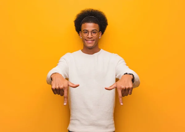 Turuncu Bir Duvarın Üzerinden Parmaklarıyla Dibini Gösteren Genç Bir Afrikalı — Stok fotoğraf