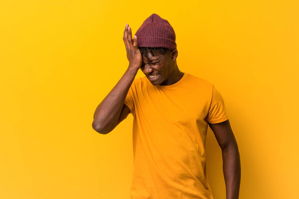 Young black man wearing rastas over yellow background forgetting something, slapping forehead with palm and closing eyes.