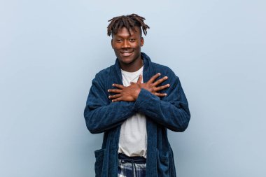 Pijama giyen Afrikalı genç bir adamın, avuçlarını göğsüne bastıran dostane bir ifadesi var. Aşk konsepti.