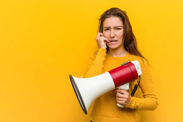 年轻的欧洲女人拿着扩音器咬着指甲 紧张而焦虑 — 图库照片