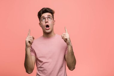 Young cool caucasian man pointing upside with opened mouth.