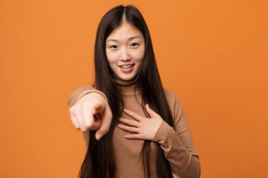 Genç güzel çinli kadın işaret başparmak parmak uzakta, gülerek ve kaygısız.