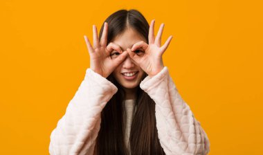 Pijamalı genç Çinli kadın gözlerinde sorun yok işareti gösteriyor.