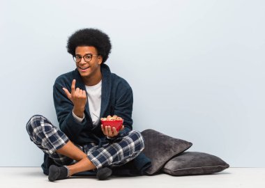 Genç siyah adam oturuyor ve kahvaltısını ediyor.