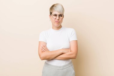 Young authentic natural woman wearing a white shirt unhappy looking in camera with sarcastic expression.