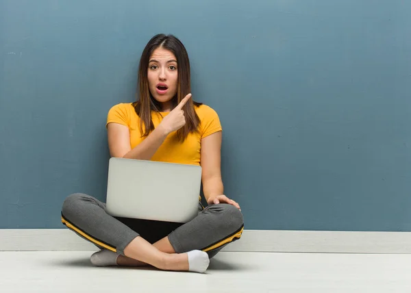 若い女性が床に座っているノートパソコンが横を向いている — ストック写真