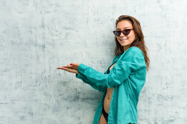 Young european woman wearing bikini holding a copy space on a palm.