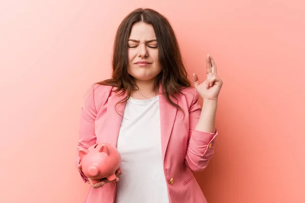 Young Size Curvy Business Woman Holding Piggy Bank Crossing Fingers — 스톡 사진