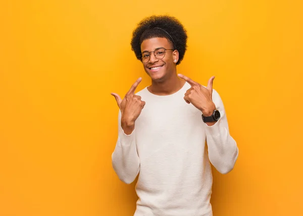 Joven Afroamericano Sobre Una Pared Naranja Sonríe Señalando Boca — Foto de Stock