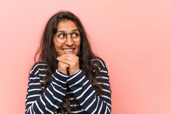 Young intellectual indian woman keeps hands under chin, is looking happily aside.