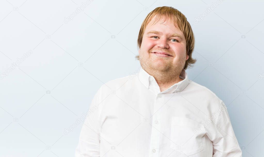 Young authentic redhead fat man laughs and closes eyes, feels relaxed and happy.