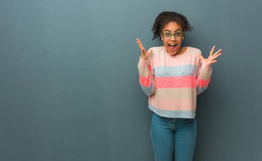 Mavi gözlü genç Afrikalı Amerikalı kız zaferi ya da başarıyı kutluyor.