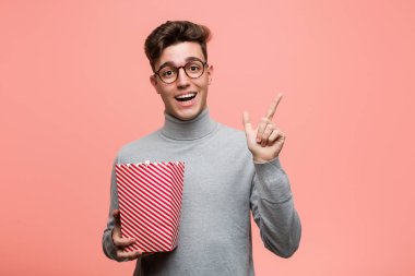 Genç entellektüel adam elinde patlamış mısır kovasıyla seni işaret ediyor sanki davet ediyormuş gibi..