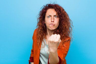 Genç kızıl saçlı zarif kadın kameraya yumruğunu gösteriyor, agresif yüz ifadesi..