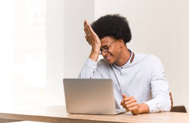 Genç siyah adam laptopunu unutkan kullanıyor, bir şeyi fark ediyor.