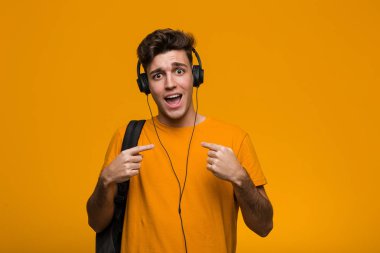 Kulaklıkla müzik dinleyen genç havalı öğrenci kameraya yumruğunu gösteriyor, agresif yüz ifadesi..