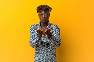 Tatil giymiş genç siyah Rasta adam. Dudaklarını kıvırıp avuç içi tutarak hava öpücüğü gönderiyor..