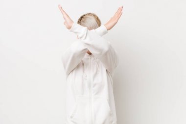 Beyaz kapüşonlu genç kadın iki kolu çapraz tutuyor, inkar kavramı.