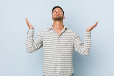 Genç yakışıklı Filipinli adam gökyüzüne doğru bağırıyor, yukarı bakıyor, hayal kırıklığına uğramış.