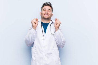 Yakışıklı doktor yumruğunu kaldırıyor, mutlu ve başarılı hissediyor. Zafer konsepti.