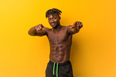 Genç siyah adam mayosuz, neşeli gülücükler takıyor..