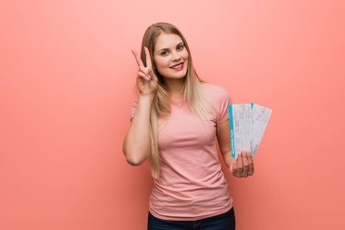 Genç, güzel, Rus bir kız zafer jesti yaparak eğleniyor ve mutlu oluyor. Elinde uçak bileti var..