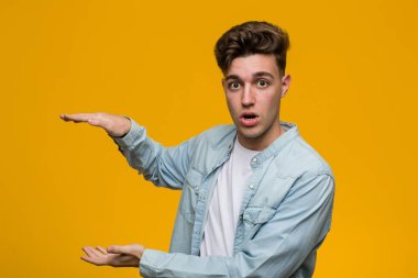 Kot gömlek giyen genç ve yakışıklı öğrenci ellerinin arasında bir kopya alanı tutarken şok ve hayrete düştü..