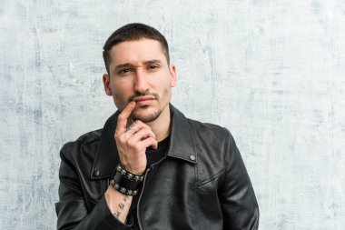 Genç rockçı şüpheli ve şüpheci bir ifadeyle yana bakıyor..