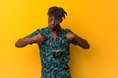 Tatil kıyafeti giyen genç siyah Rasta kendini göstererek şaşırmış, geniş bir gülümseme içinde..