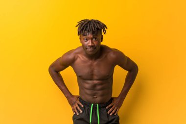 Genç, siyah, üstsüz, mayosuz bir adam çok kızgın birini azarlıyor..