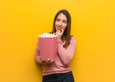 Elinde patlamış mısır kovası olan genç, tatlı bir kadın rahatlamış fotokopi odasına bakan bir şey düşünüyor.