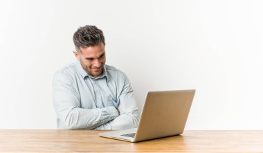 Genç yakışıklı adam dizüstü bilgisayarıyla gülüyor ve eğleniyor..