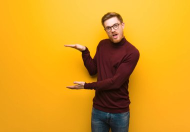 Genç akıllı adam elinde çok şaşırmış ve şok olmuş bir şey tutuyor.