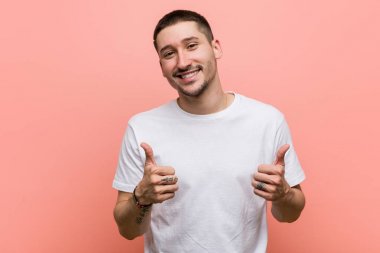 Genç adam iki parmağını da kaldırıyor, gülümsüyor ve kendinden emin..