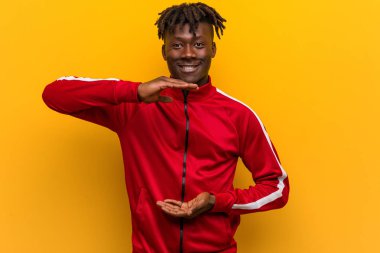 Genç fitness siyah adam iki eliyle bir şey tutuyor, ürün sunumu..