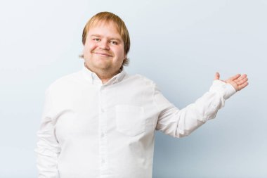 Genç otantik kızıl saçlı şişman adam avucunun içinde fotokopi odası gösteriyor ve belinde bir el daha tutuyor..