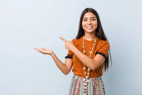 Young arab woman excited holding a copy space on palm.