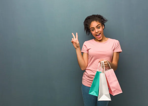 Young black woman doing a gesture of victory. She is holding a shopping bags.